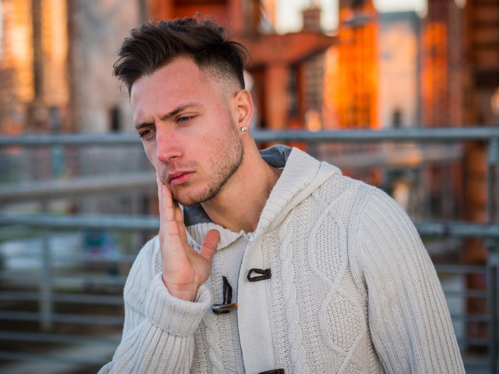 Young handsome man standing, in pain, suffering from toothache